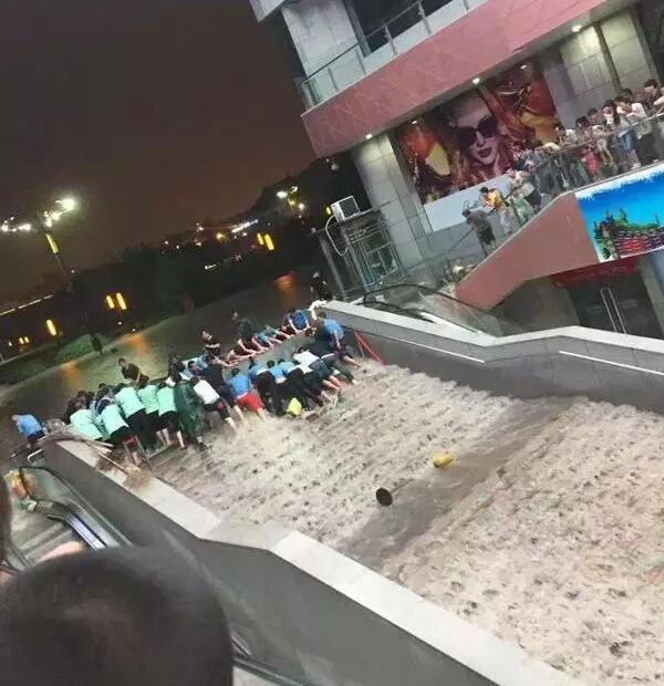 汉唐书城的员工正在合力阻挡洪水进入负一层，还有个小视频，有几个同志被洪水冲下去了，也不知道有没有受伤。汉唐加油！